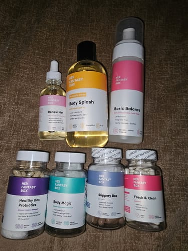 Reviewer's bottle of Healthy Box Probiotics shown with other wellness products from the same brand on a dark surface.