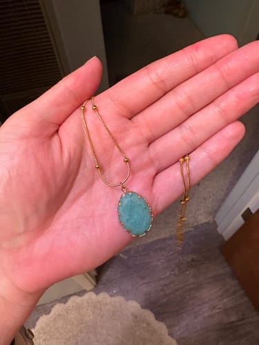 Customer holding the beautiful necklace with a blue stone from their AuraBloom Subscription Box.