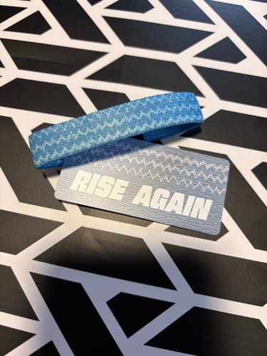 Customer's blue Rise Again Bible Verse Bracelet and matching card on a patterned surface.