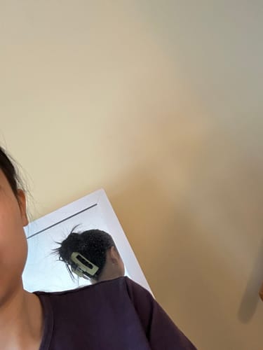 Reviewer's reflection in a mirror, showing a light-colored cloud clip holding their dark hair up.
