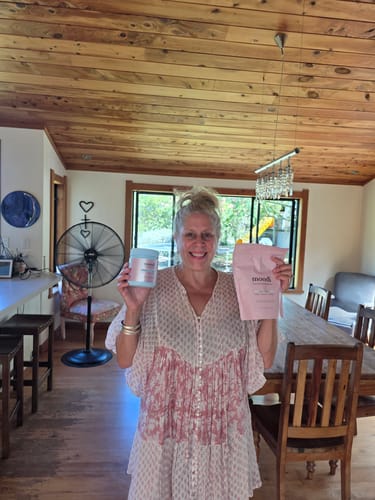 Reviewer smiling while holding the Classic Pre + Probiotic Bundle, which includes a tub and a pouch, in their home.