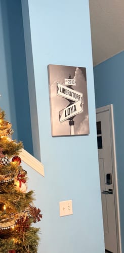 Customer's personalized street sign canvas showing the names 'Liberatore' and 'Loya' hanging on a blue wall.