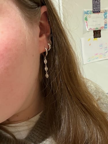 Customer wearing the silver Drip Marquise huggies in an ear stack with other small hoop earrings.