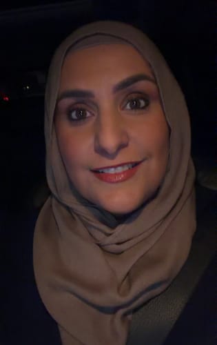 Reviewer smiling while wearing a light brown hijab that stays perfectly in place.