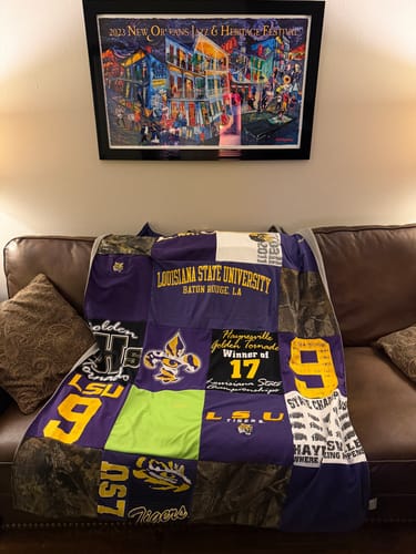 Customer's Premium T Shirt Quilt with LSU and sports-themed shirts draped over a brown leather couch.
