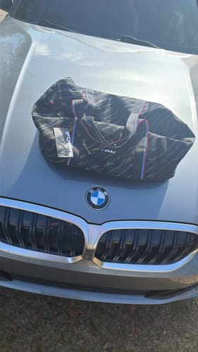 Reviewer's black M-POWER duffle bag displayed on the hood of a silver BMW car.
