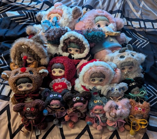 Reviewer's full collection of the plush MayMei Winter Weirdness Series blind box toys piled on a bed.