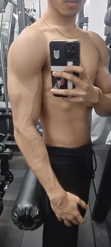 Reviewer in a gym showing their muscular upper body, associating it with Wellcore Creatine Monohydrate.