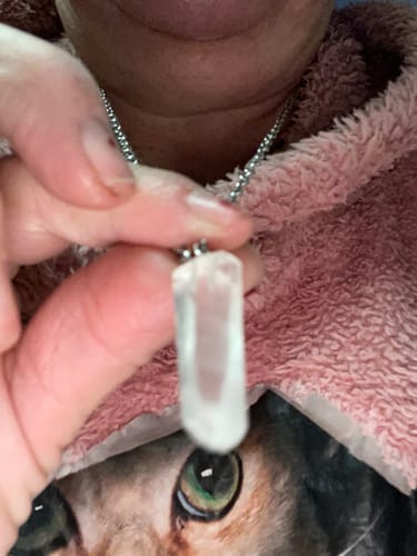 Gros plan d'une cliente tenant son pendentif transparent en Cristal de Roche.