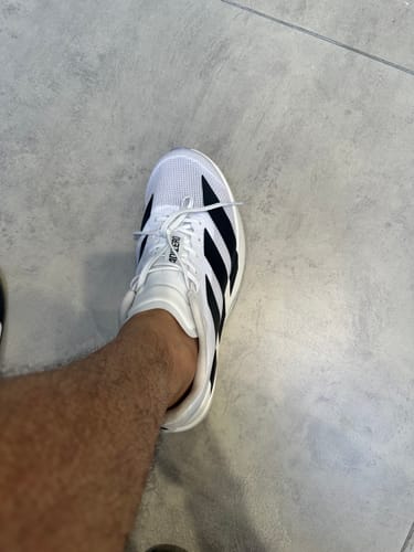 Customer trying on the white and black Adizero EVO SL Running Shoe, seen from a top-down perspective.