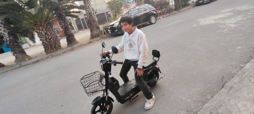 Un cliente joven sentado en su Bicicleta Eléctrica Negra Kiwo GY801 en una calle al aire libre.