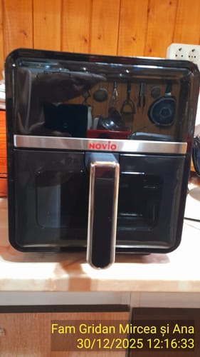 Un client prezintă friteuza neagră și lucioasă Air Fryer Novio StonePro pe un blat de bucătărie.