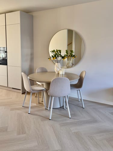 Klant toont de ronde, beige Vasso eettafel in een lichte eetkamer.