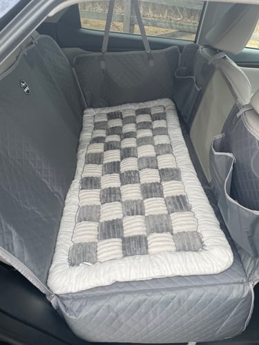 Customer's checkerboard Plush Backseat Dog Bed fitted inside a grey, quilted car seat hammock in a vehicle.