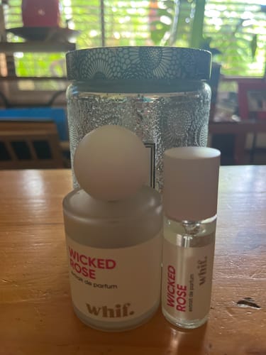 Customer's two bottles of Wicked Rose perfume, one large and one travel-sized, on a table.