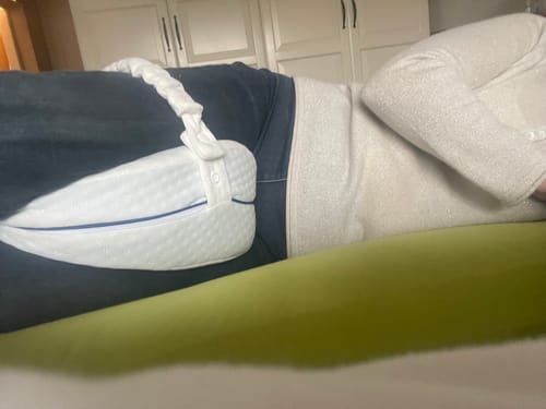 Une cliente allongée sur le côté utilise le coussin orthopédique pour genoux Cellsius entre ses jambes.