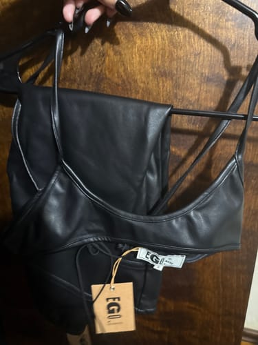 Reviewer holding the black leather EGO CAPRIS and matching top on a hanger.