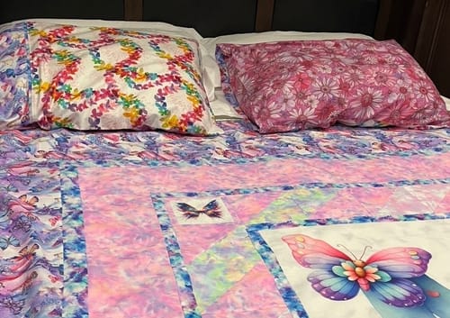 Customer's pillowcase made with the pink, floral Sleepovers quilt backing fabric, displayed on a bed.