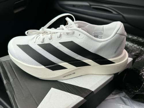 Customer's new white Adizero EVO SL Running Shoe with black stripes, shown from the side on its box.