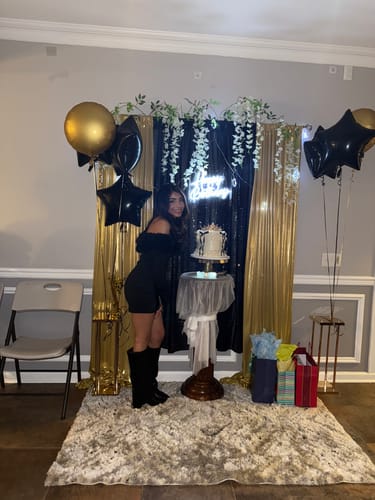 Reviewer posing in black Rivanna Foldover Boots at a party, next to a cake.
