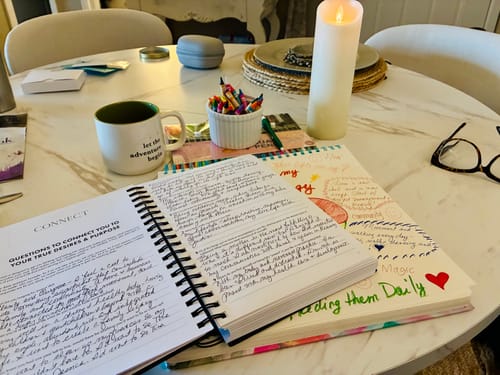 Customer's 2026 Dreambook + Planner open on a table, showing handwritten answers to reflection questions.