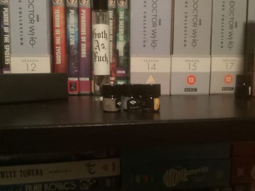 Customer's set of 5 1ml sample vials displayed on a dark shelf in front of a DVD collection.