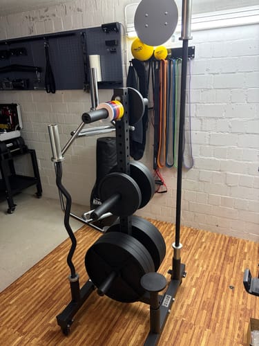 Customer's black Deep Dish Cast Iron Plates neatly organized on a weight rack in a home gym.