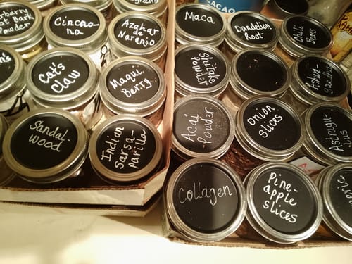 Customer's organized herbs and dried foods in sealed mason jars with handwritten labels, demonstrating the vacuum sealer system.