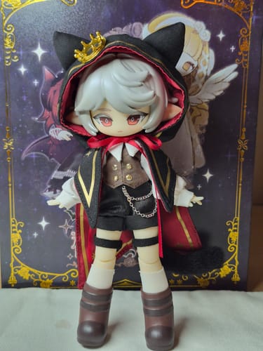 Customer's Astra BJD action figure standing fully dressed in its black hooded cape with a gold crown and cat ears.