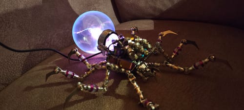 Reviewer's assembled Cyberpunk Plasma Ball Spider with its glowing purple plasma ball lit up on a couch.