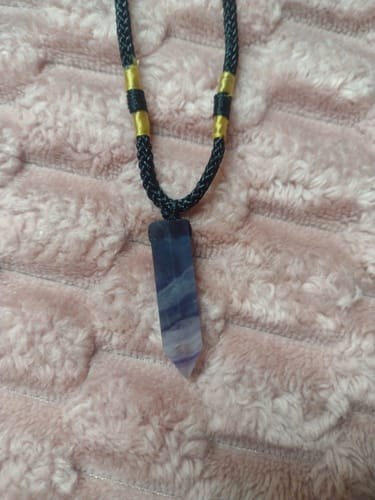 Close-up of a reviewer's Natural Fluorite Necklace showing the purple crystal on a black cord.