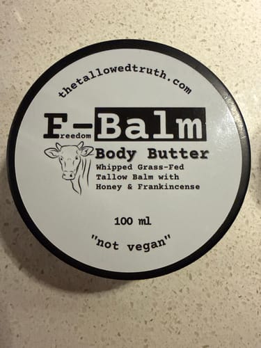 A customer's F-Balm Whipped Body Butter container. The white label includes a cow illustration and the words 'not vegan'.