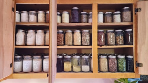 Customer's pantry with dry goods neatly organized in glass jars, a result of using the stainless steel funnel.