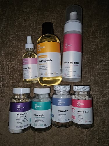 Reviewer's collection of Her Fantasy Box products, including the Renew Her Yoni Oil in a dropper bottle.