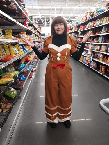 Reviewer wearing the brown Gingerbread jumpsuit with a black turtleneck in a store aisle.