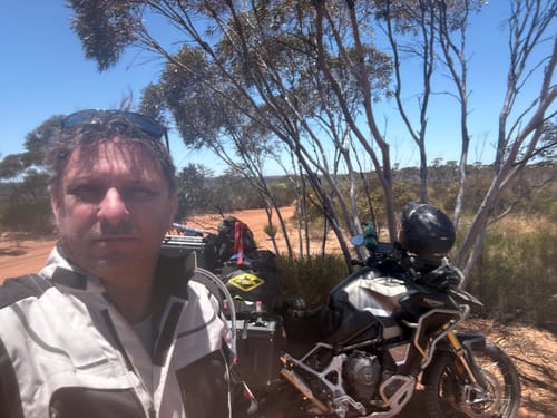 Reviewer with his motorcycle featuring the Wind Rider Seat Cover on a sunny, rugged trail.