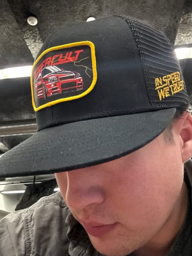Reviewer wearing the black SKYLINE TRUCKER HAT, showing the front patch with a red car and side embroidery.