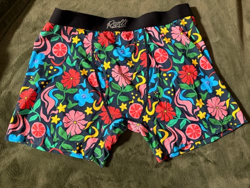 Reviewer's colorful Groovy Garden boxer briefs with a floral pattern laid out flat on a bed.