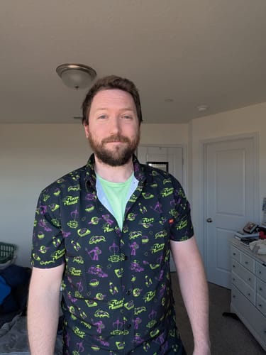 Reviewer wearing the patterned Toy Story 'Cleared to Enter' shirt over a light green t-shirt.