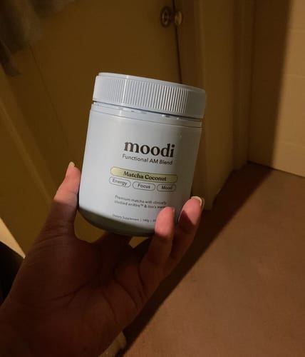 Reviewer holding the light blue jar of Matcha Coconut AM Blend.