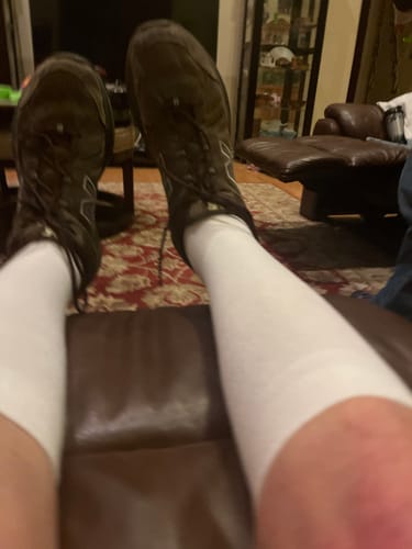 Partial view of a customer wearing white Performance Eucalyptus Compression Socks with dark shoes while resting.