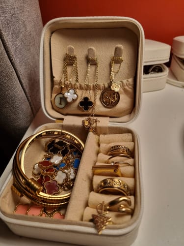 Customer's Marble Initial Necklace hanging in an open jewelry box filled with their gold collection.