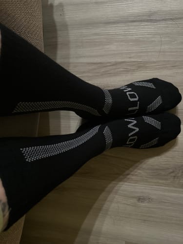 Reviewer's feet wearing the black Women's Alpaca Socks, showing the fit and grey patterned accents.