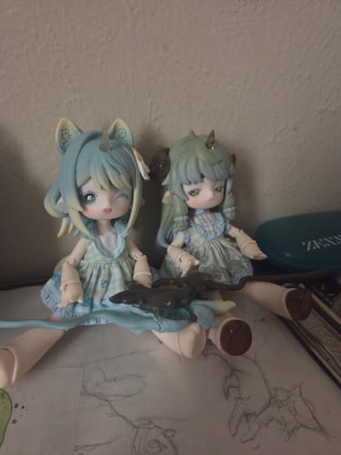 Customer's two Antu Cute Beast BJD figures sitting on a desk. One figure has blue hair and winks, the other has green hair.