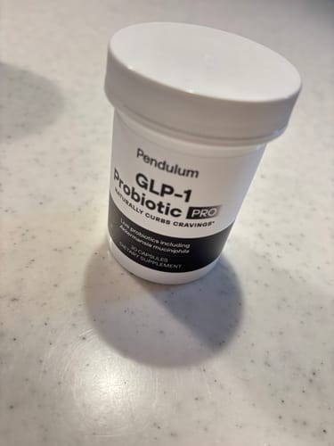 購入者のGLP-1 プロバイオティクス サプリメントの白いボトルがカウンターの上に置いてある。