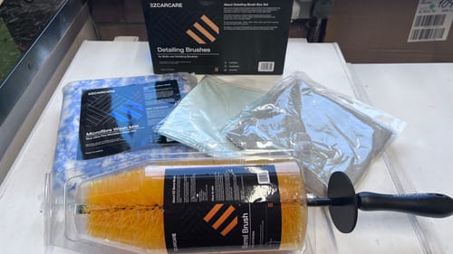 Customer's EZ Car Care detailing tools, including various brushes, a wash mitt, and cloths, laid out on a surface.