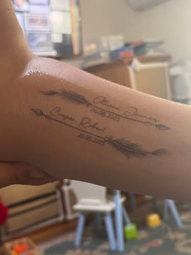 Customer's arm with a fresh, new tattoo of two arrows after using the Painless Tattoo Numbing Cream.