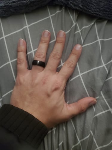 Customer's hand wearing the black silicone wedding ring with a visible stainless steel strip.