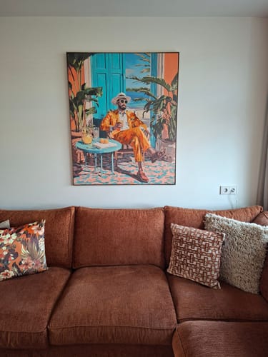 Klant toont het by fonQ Tropic Gent Schilderij hangend boven een roestbruine bank in hun woonkamer.