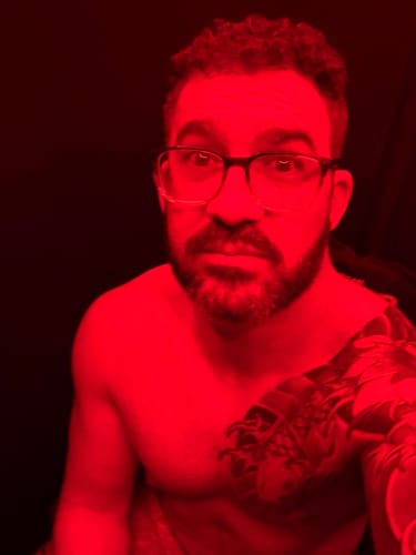 Close-up of a reviewer with glasses inside the red-lit sauna from the Contrast Therapy Bundle.